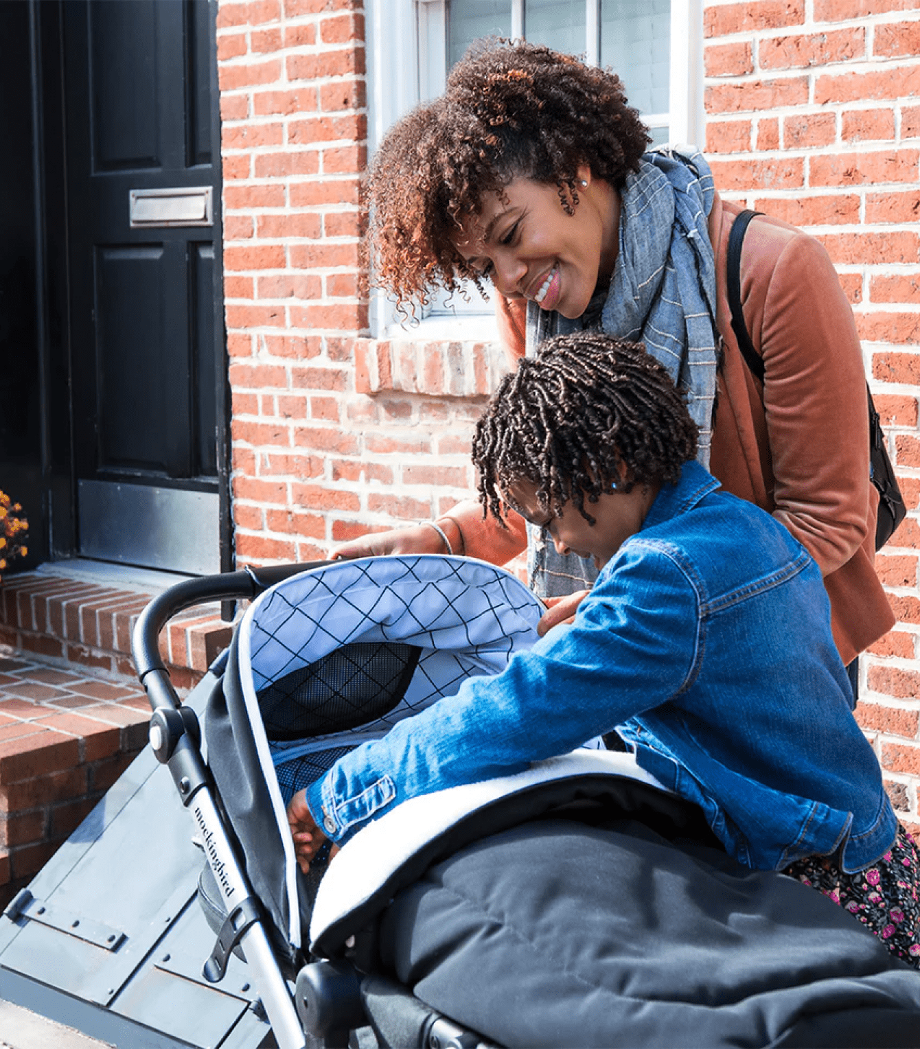 Mother and her daughter smiling and checking on baby in the stroller